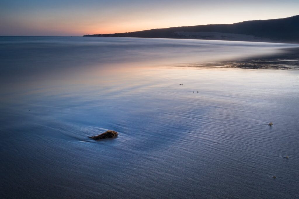 Serene twilight scene of a peaceful seashore with gentle waves and warm hues.