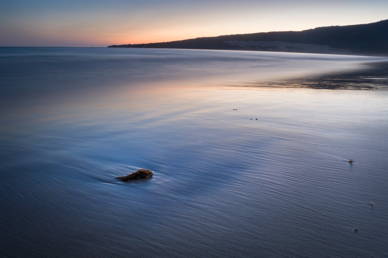 Serene twilight scene of a peaceful seashore with gentle waves and warm hues.