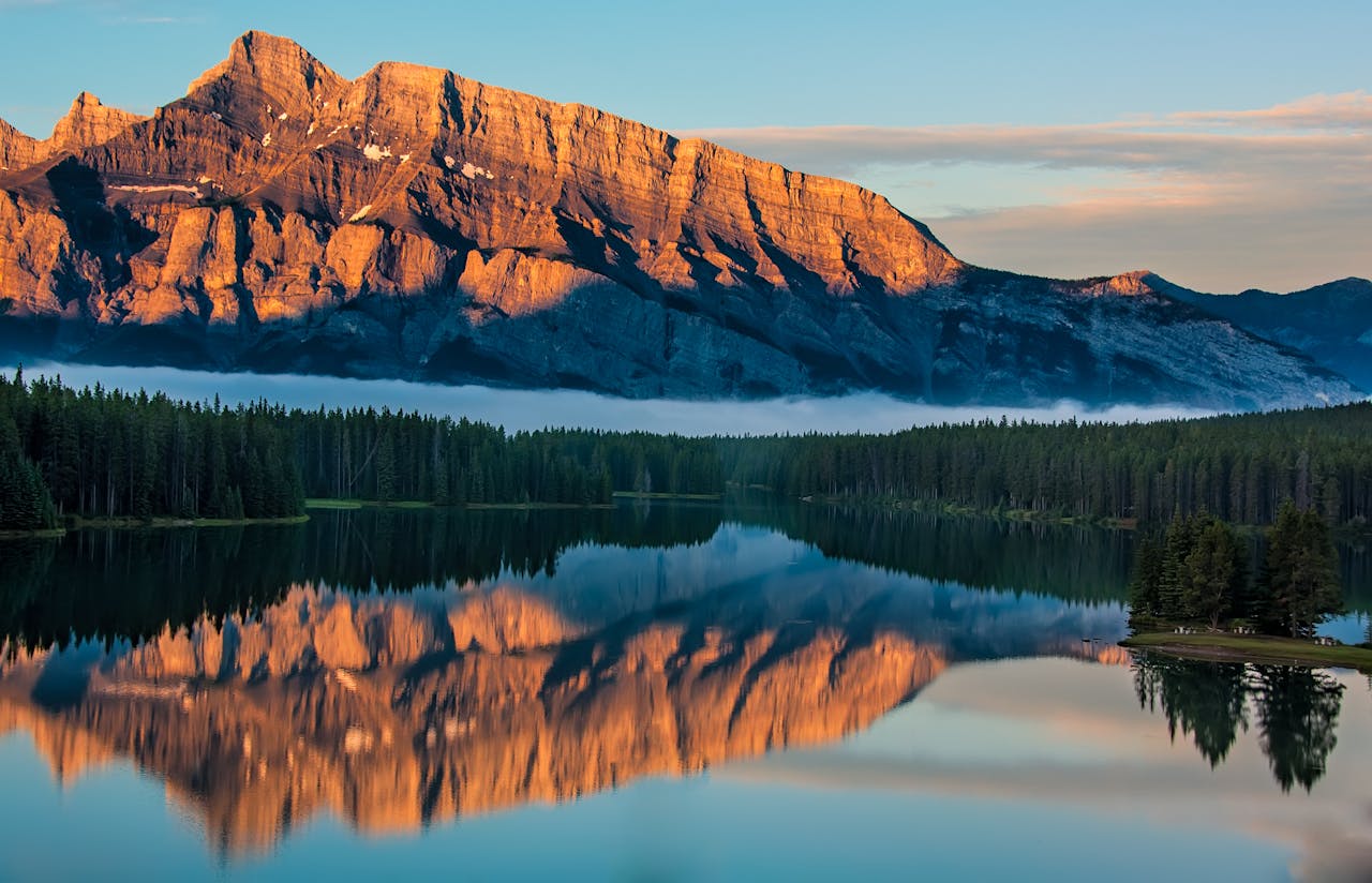 Capture of a serene lake reflecting majestic mountains at sunrise in the wilderness.