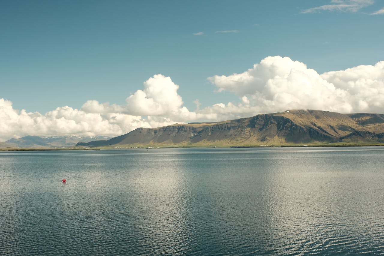 Breathtaking view of Mount Esja with clouds over ocean in Reykjavík, Iceland.